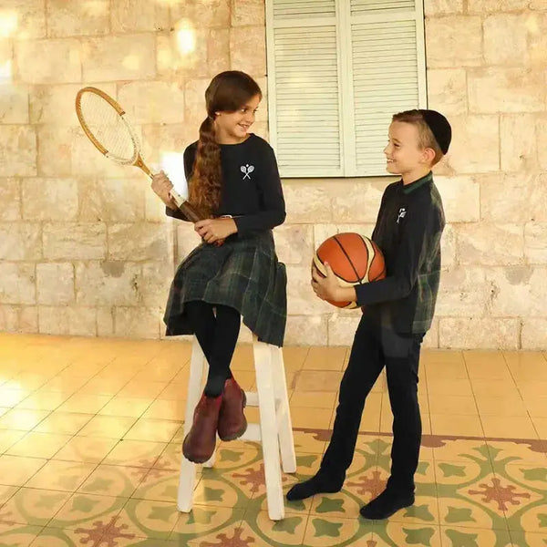 Young girl dressed in a tennis embroidery plaid set, sporty matching sister style for active family play.