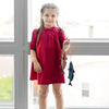 Little lady dressed in a boat print red denim set, stylish matching sister outfit for fun family outings.