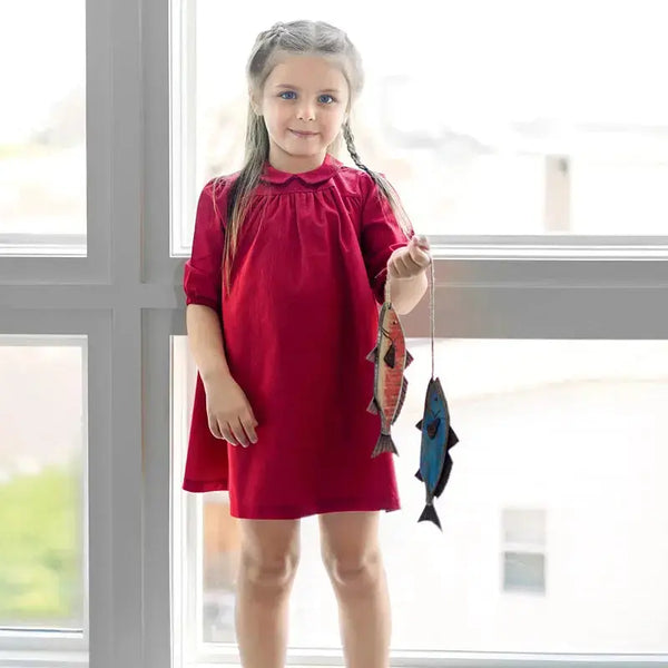 Little lady dressed in a boat print red denim set, stylish matching sister outfit for fun family outings.