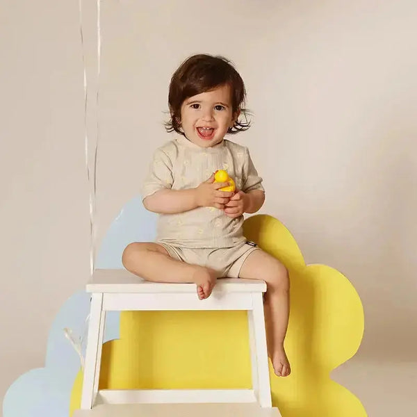 Baby dressed in a ribbed sunshine bow detailed set, sunny matching sibling outfit for bright family celebrations.