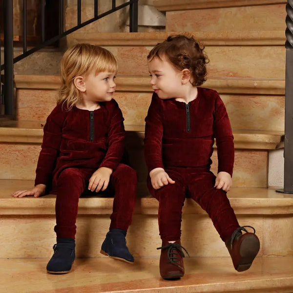 Adorable baby in a burgundy red chenille soft set, warm matching sibling style for cozy family gatherings.