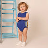 Baby in a striped pocket detailed set, nautical matching sibling outfit for seaside family adventures.